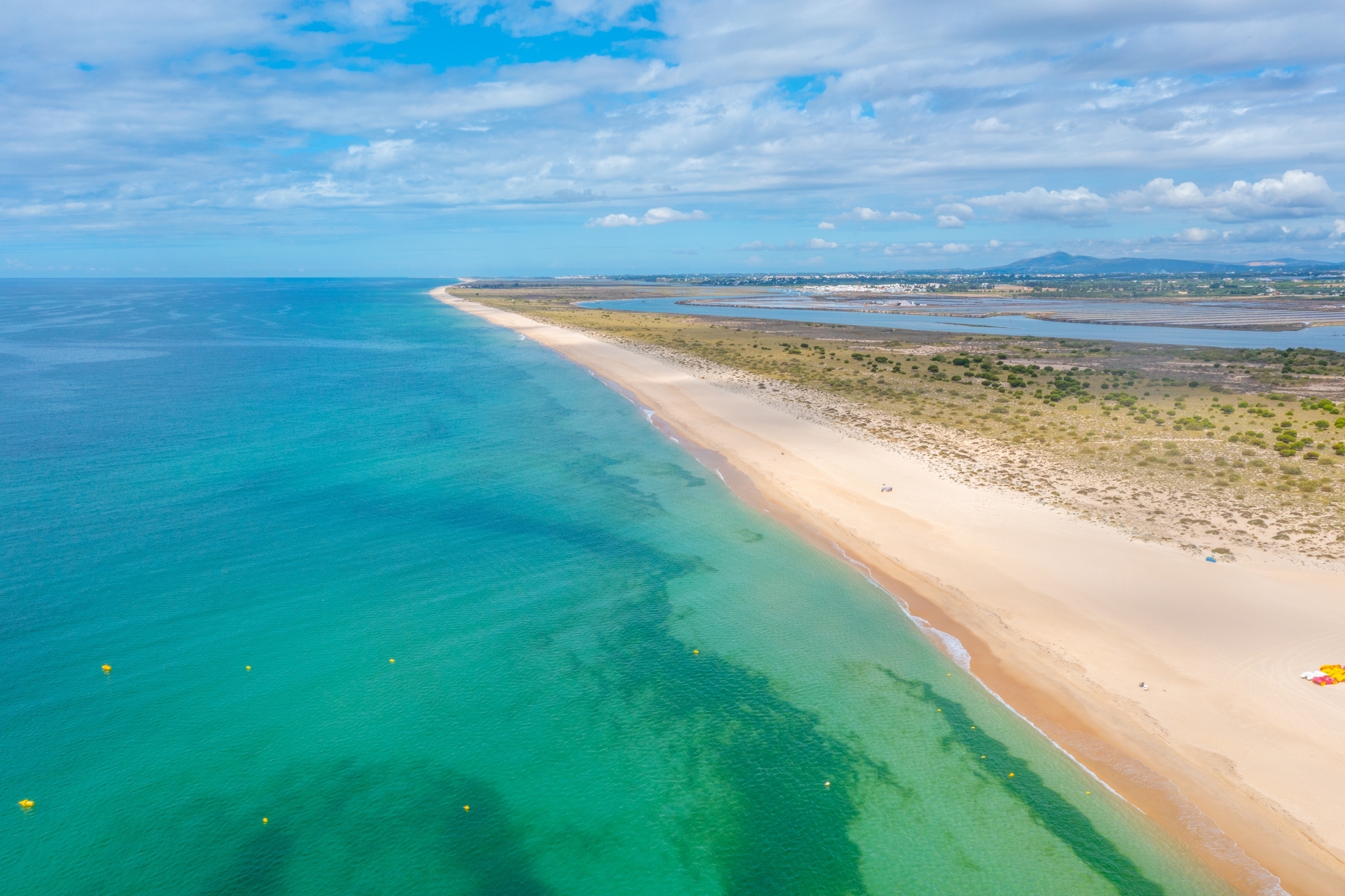 Luftfoto af den idylliske Ilha de Tavira strand med parasol og solsenge langs Algarvekysten i Portugal