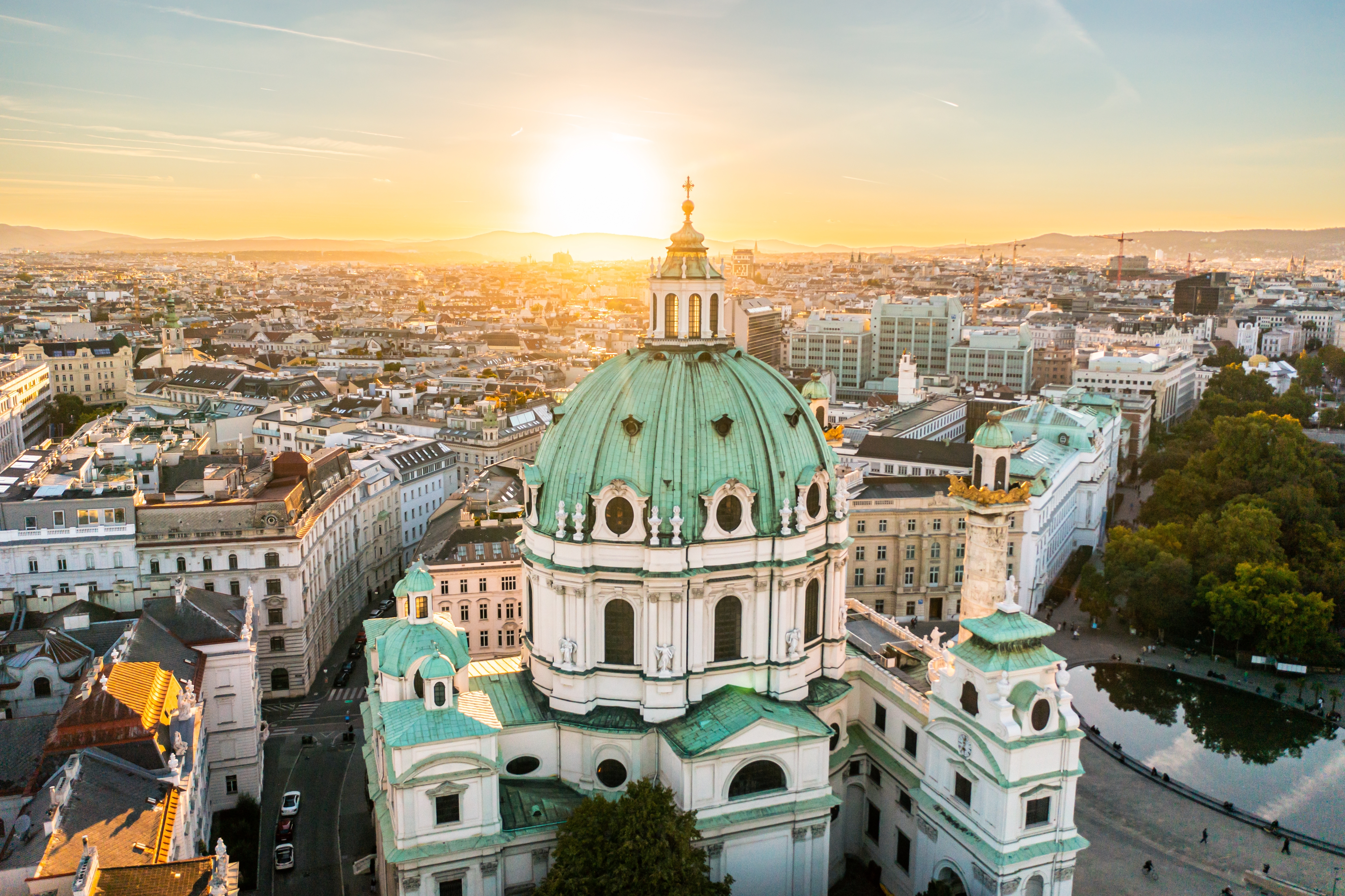 Luftfoto af Karlskirche i Wien ved solnedgang, der viser den barokke arkitektur og kuppel.