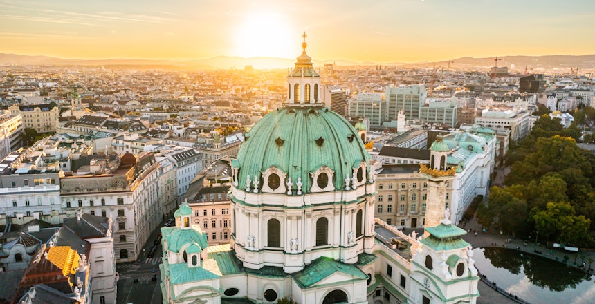 Luftfoto af Karlskirche i Wien ved solnedgang, der viser den barokke arkitektur og kuppel.