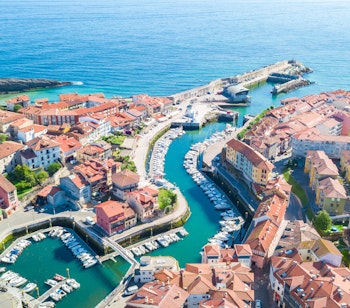 Betagende luftfoto af den charmerende fiskerlandsby Llanes ved kysten i Asturien, Nordspanien, med smukke strande og azurblåt hav