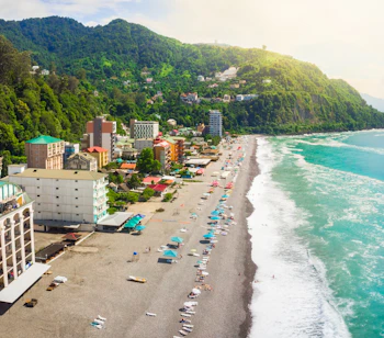 Panoramaudsigt over Sarpi-stranden ved Sortehavet i Georgien nær Batumi med turkisblåt vand, hoteller og grønne bjerge