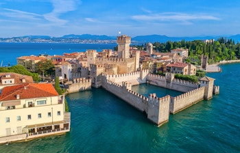 Luftfoto af den historiske by Sirmione på en halvø i Gardasøen med dens middelalderborg og azurblå vand