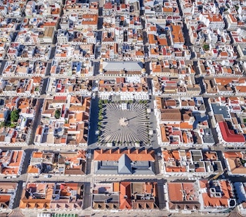 Luftfoto af den geometriske byplan i Vila Real de Santo Antonio i Algarve, Portugal, med farverige bygninger og den historiske plads ved Guadiana-floden