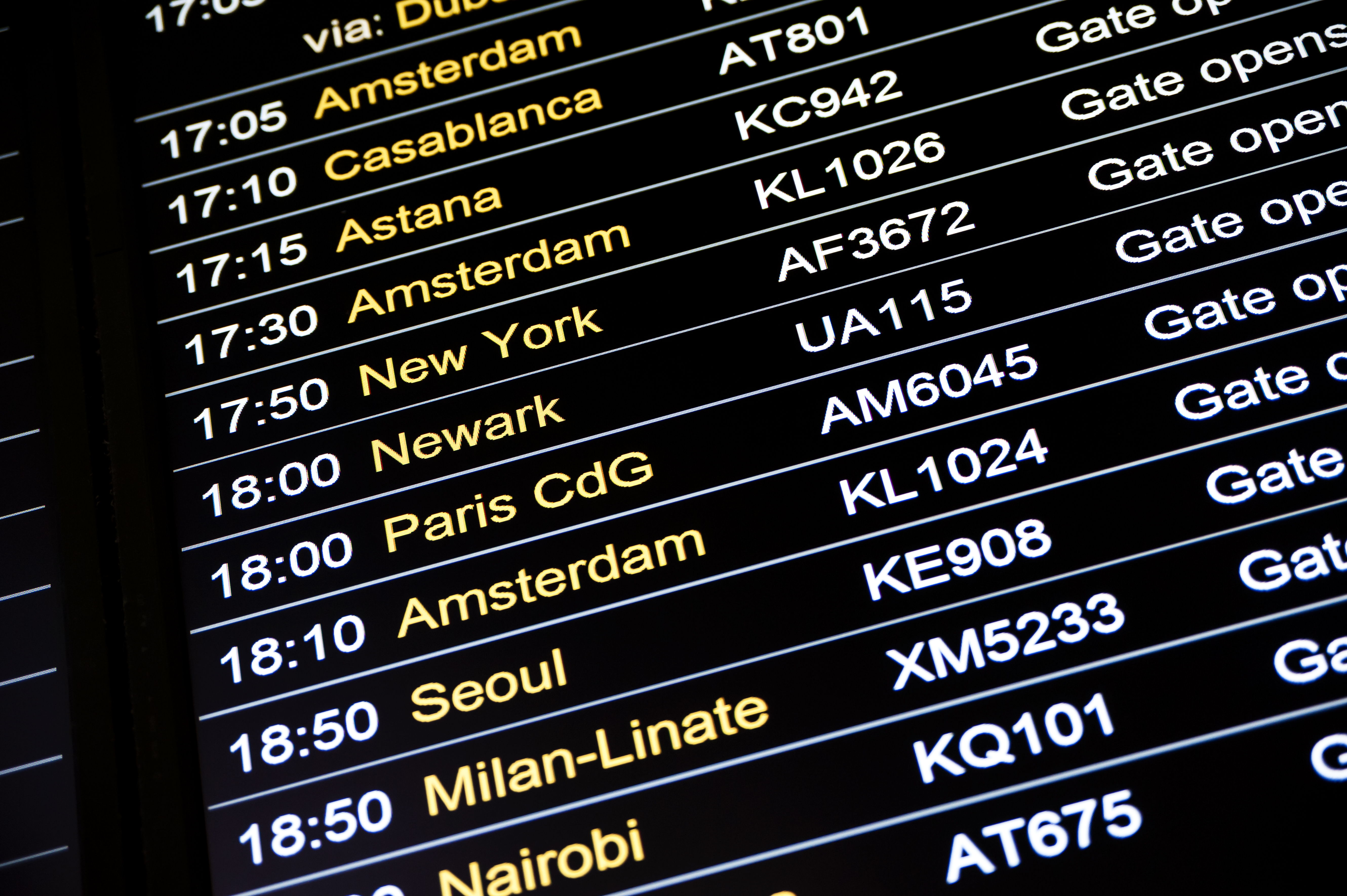 Digital afgangstavle i lufthavnsterminal der viser internationale flyafgange til populære destinationer som Amsterdam, Paris og New York