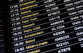 Digital afgangstavle i lufthavnsterminal der viser internationale flyafgange til populære destinationer som Amsterdam, Paris og New York