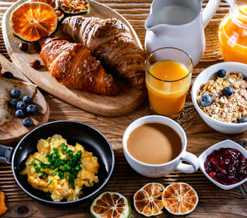 Luksuriøs morgenmadsbuffet med friske croissanter, røræg, kaffe og appelsinjuice på dansk hotel