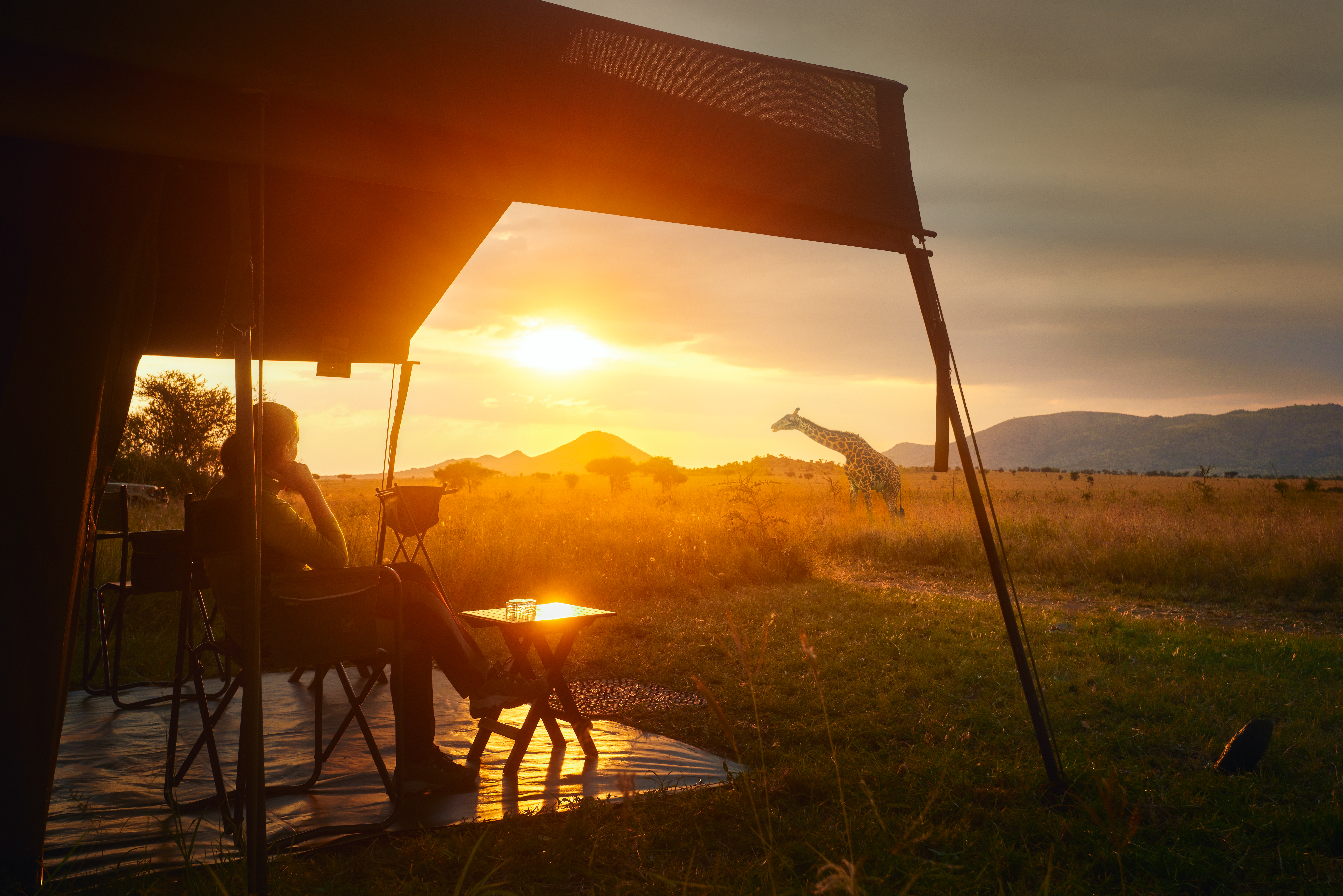 Kvinde nyder solnedgangen fra luksuriøst safaritelt i Serengeti Nationalpark, Tanzania - perfekt til eventyrrejser i Afrika