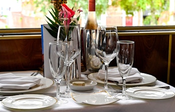 Elegant borddækning med vinglas og blomsterdekoration i en luksuriøs vintage togvogn