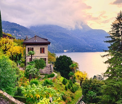 Eksklusiv historisk villa med frodige haver beliggende ved Comosøens azurblå vand nær Milano i Norditalien med bjerge i baggrunden
