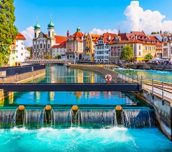 Malerisk panoramaudsigt over Luzerns gamle bydel med historisk arkitektur, træbroen og Reuss-floden omgivet af de schweiziske alper