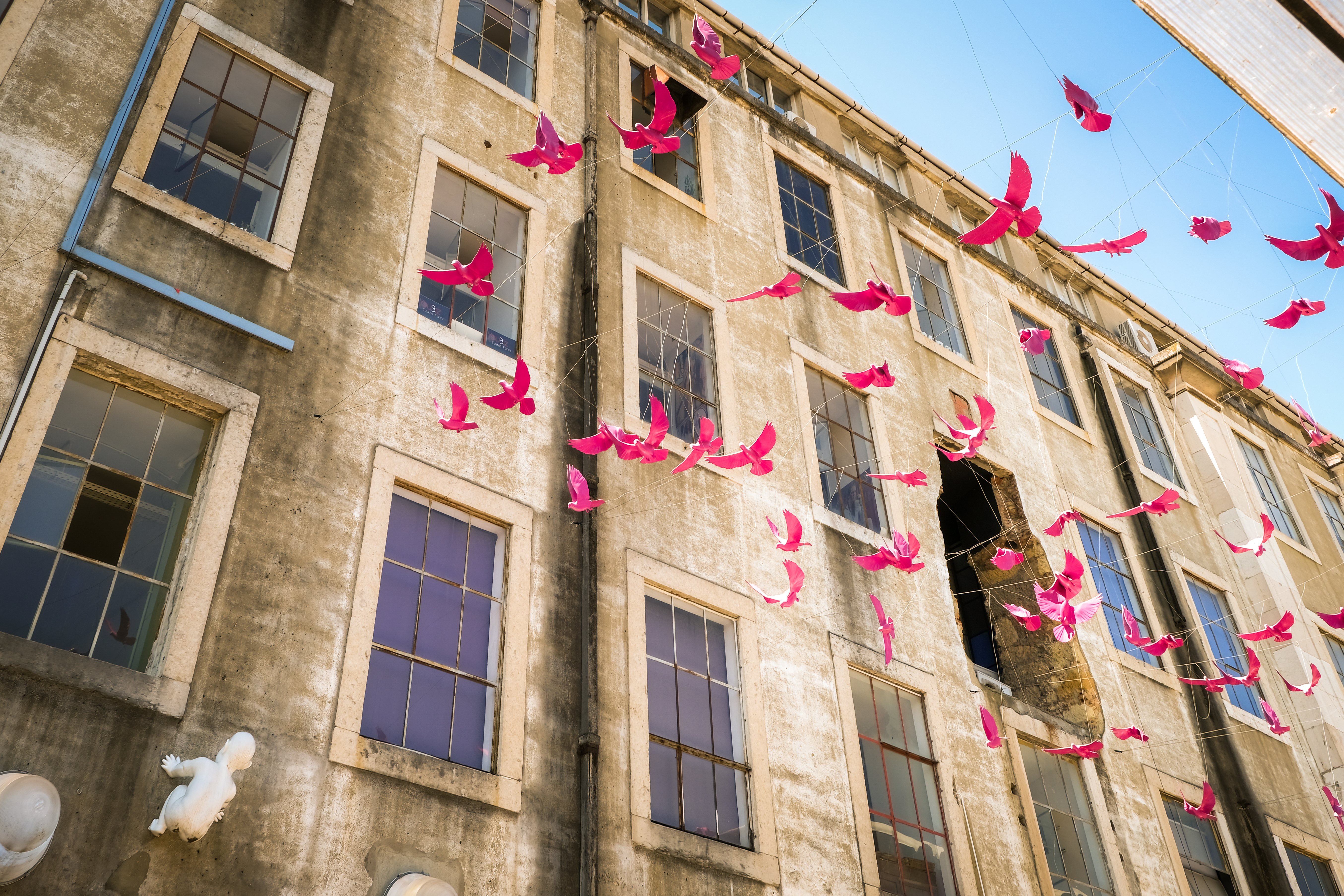 Charmerende pink bygning i LX Factory kunstkvarteret i Lissabon med traditionel portugisisk arkitektur og balkoner