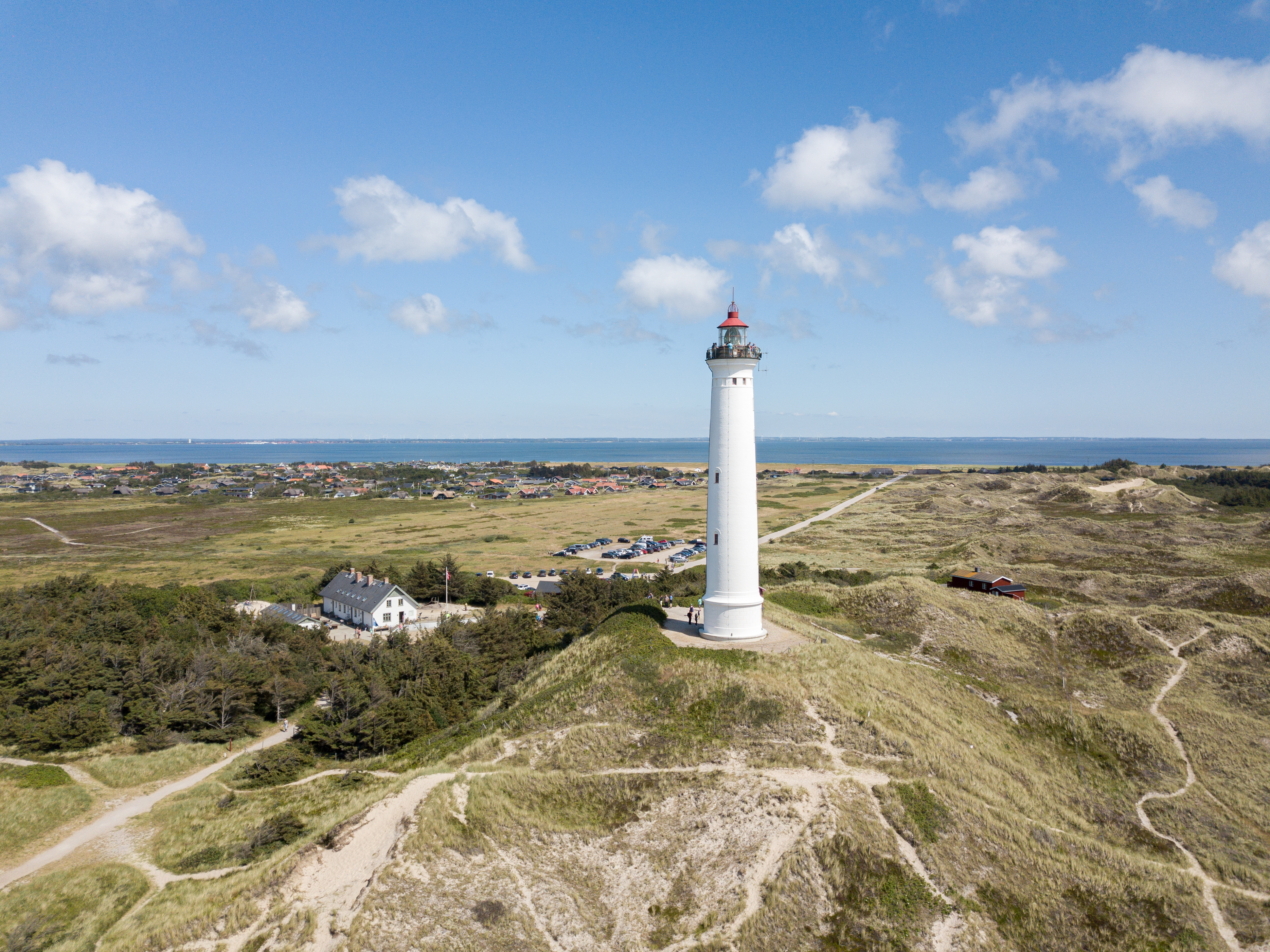 Luftfoto af Lyngvig Fyr på Jyllands vestkyst med klitter og blå himmel