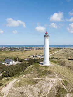 Luftfoto af Lyngvig Fyr på Jyllands vestkyst med klitter og blå himmel