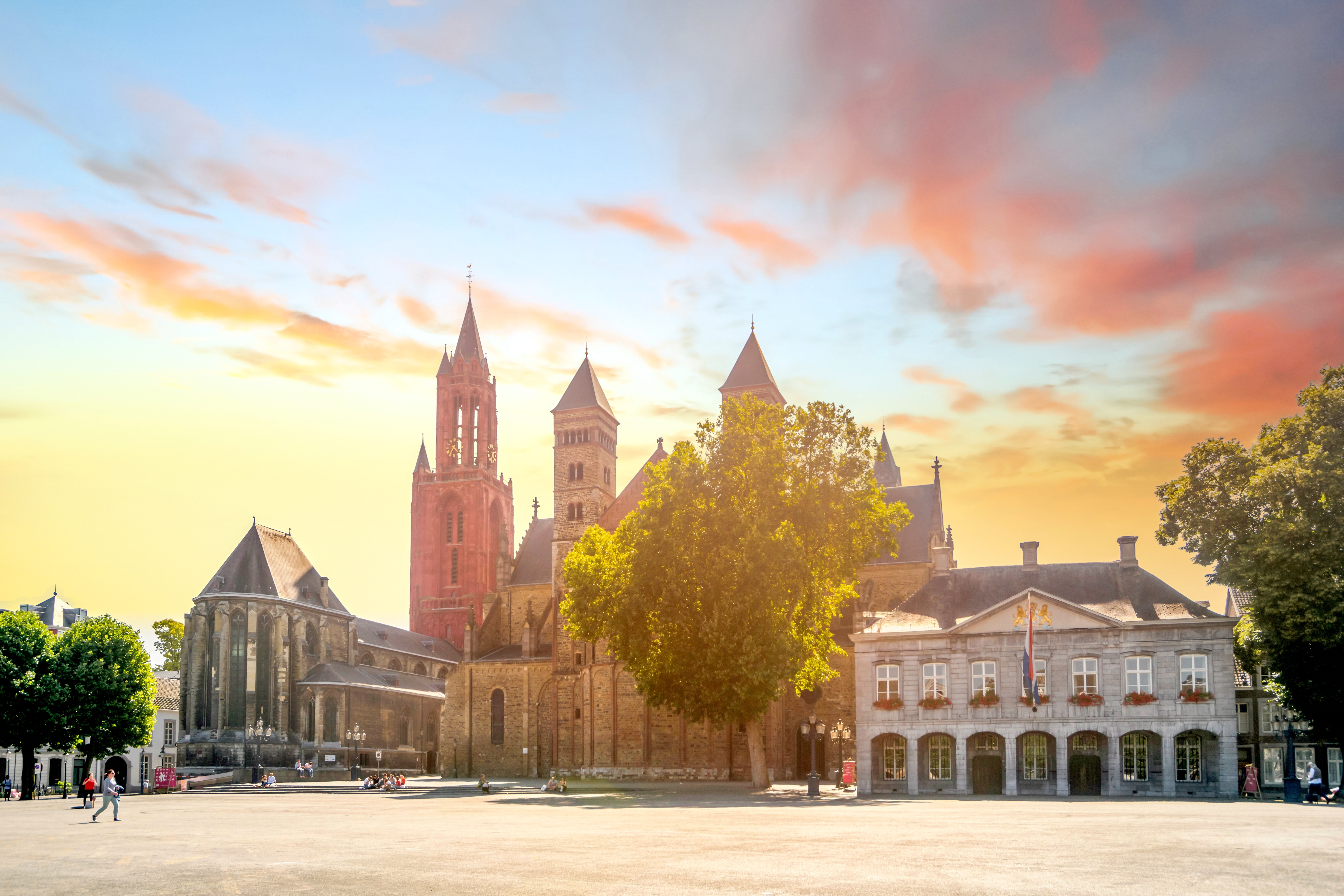 Vrijthof-pladsen i Maastricht ved solnedgang med den historiske Sankt Servatius Basilika og rådhuset under en dramatisk gylden himmel