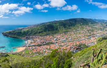 Luftfoto af Machico-bugten med sandstrand, azurblåt vand og bjerglandskab på Madeira, Portugal