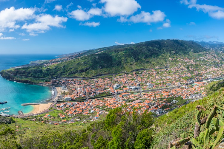 Luftfoto af Machico-bugten med sandstrand, azurblåt vand og bjerglandskab på Madeira, Portugal