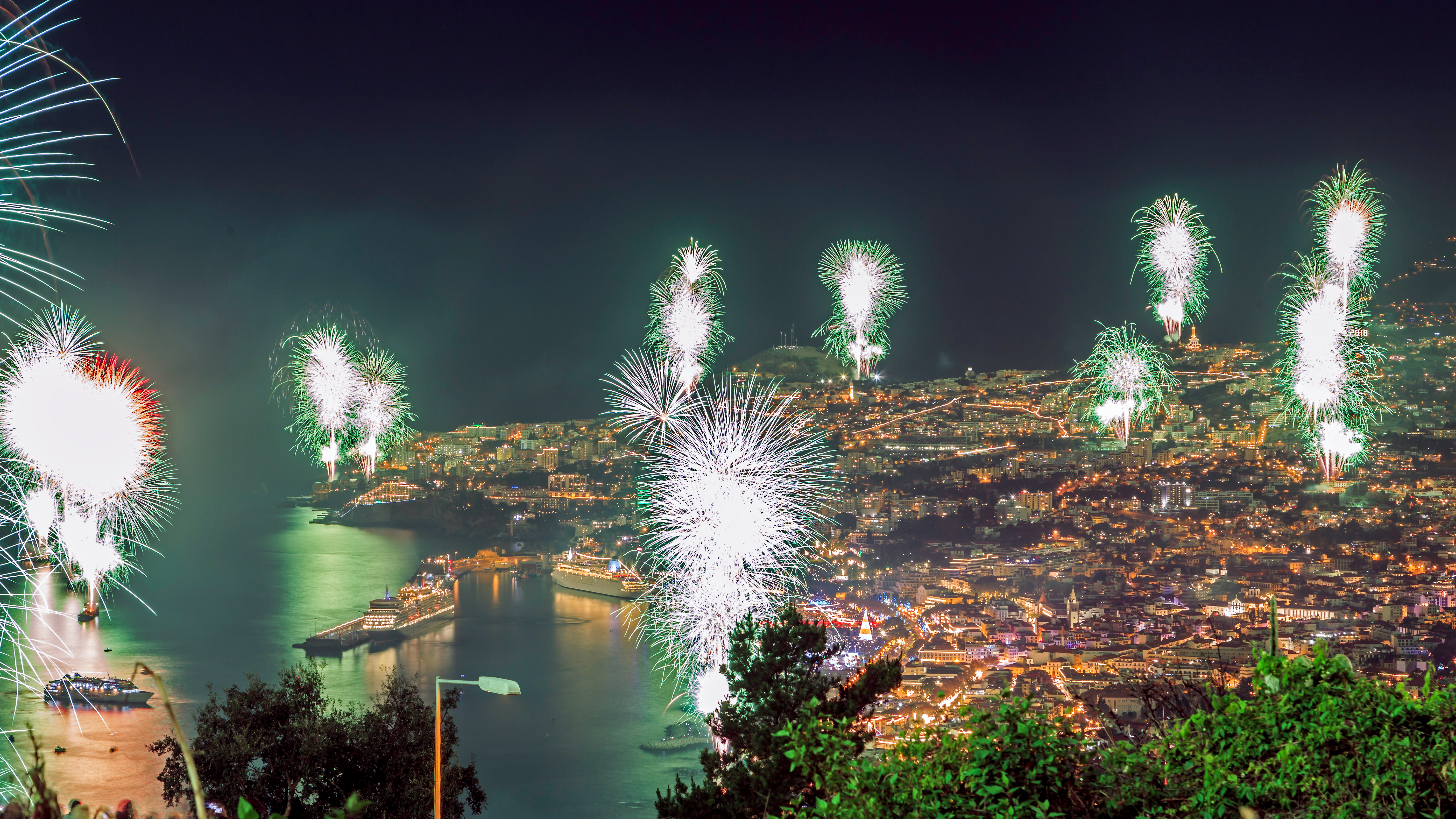 Spektakulært fyrværkeri over Madeira ø med byens lys i baggrunden om natten