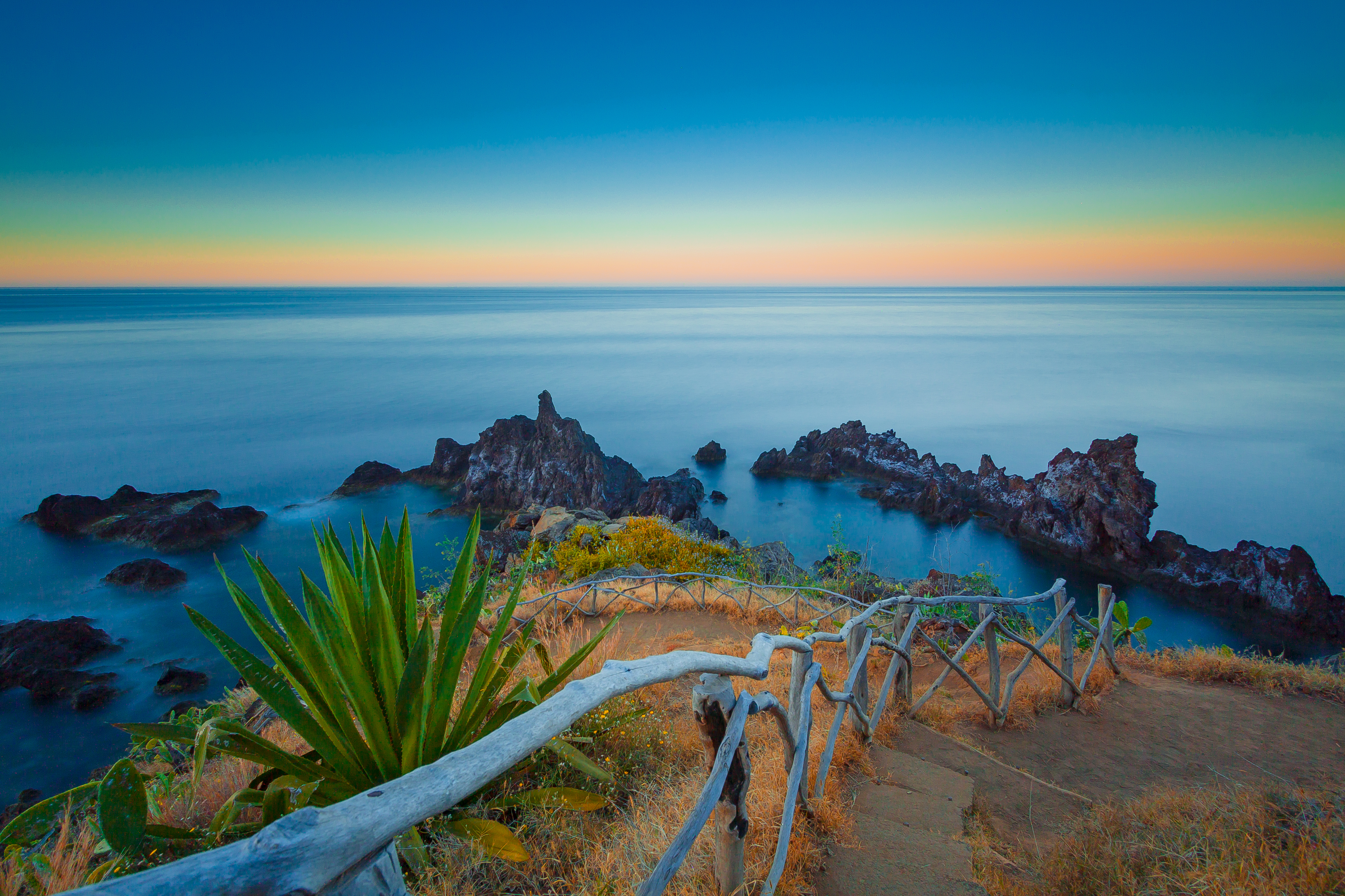 Spektakulære klipper på Madeira ved solopgang med gyldent lys der reflekteres i Atlanterhavet, Portugal
