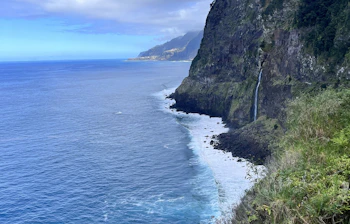 Dramatisk udsigt over Madeiras nordkyst med stejle klipper, blåt hav og frodig grøn vegetation, perfekt til vandreture og naturoplevelser