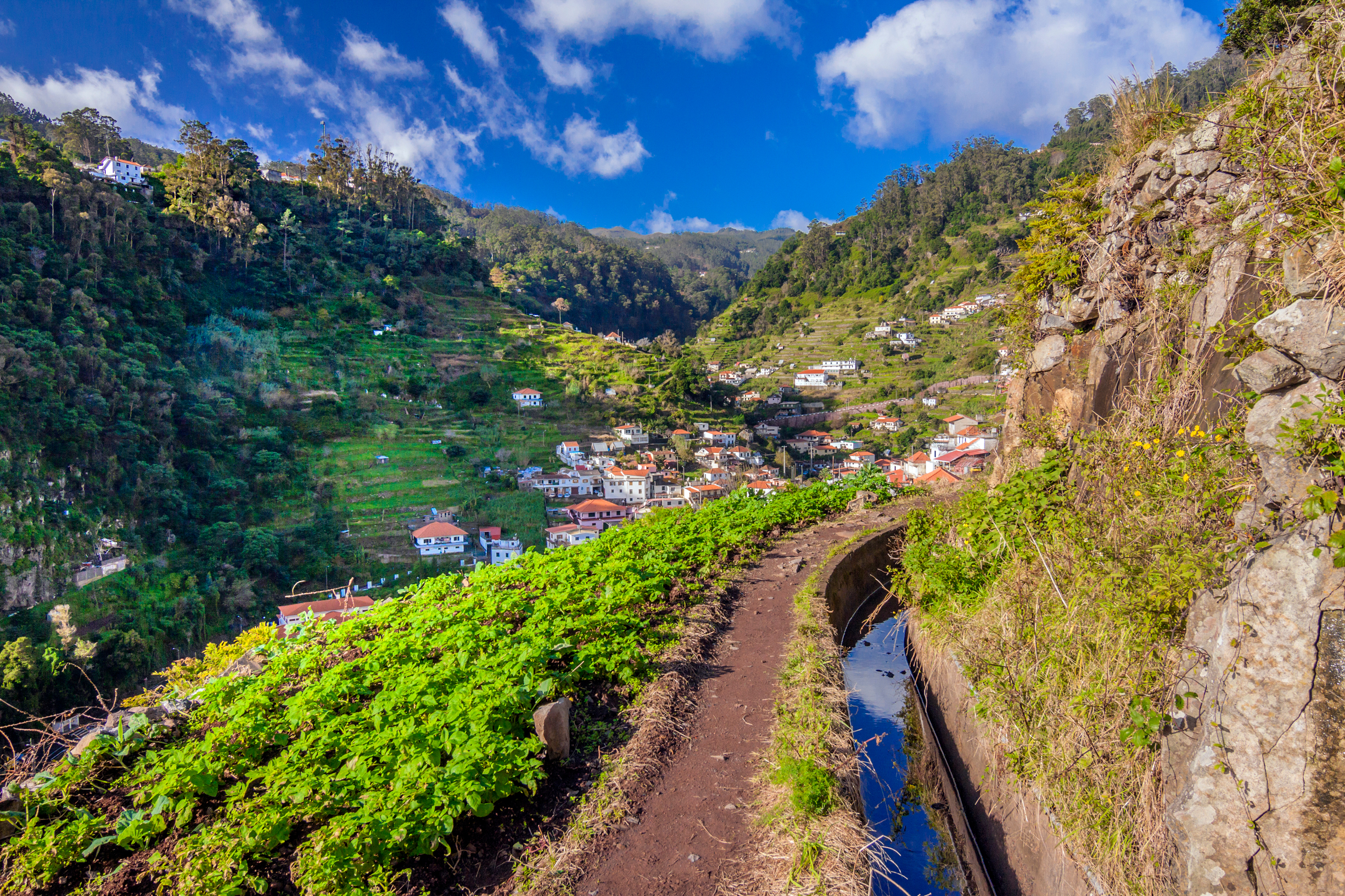 Levada vandrerute på Madeira med vandkanal over Marocos landsbyen omgivet af grønne bjerge og blå himmel