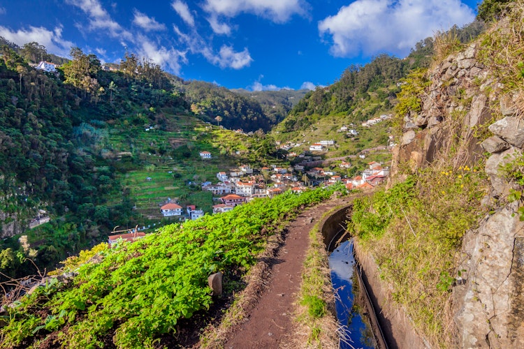 Levada vandrerute på Madeira med vandkanal over Marocos landsbyen omgivet af grønne bjerge og blå himmel