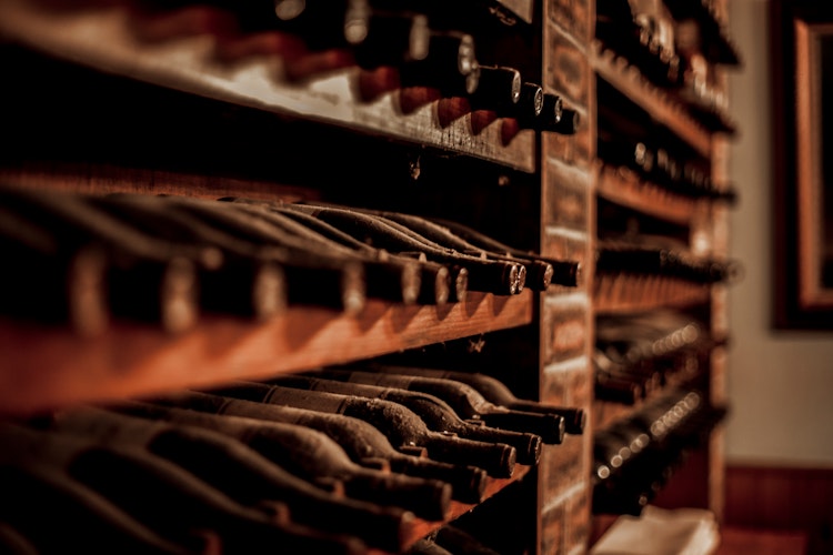 Træhylde med flasker af traditionel Madeira-vin i en vinkælder på Madeira, som kan opleves under vinsmagning i Camara de Lobos