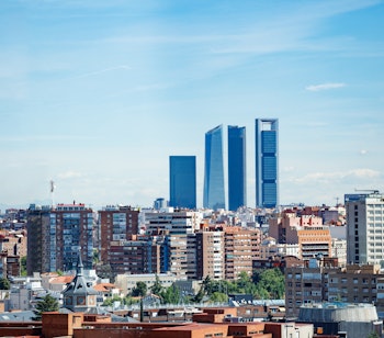 Madrid bylandskab med Cuatro Torres forretningsdistrikt og moderne skyskrabere over boligområder under blå himmel