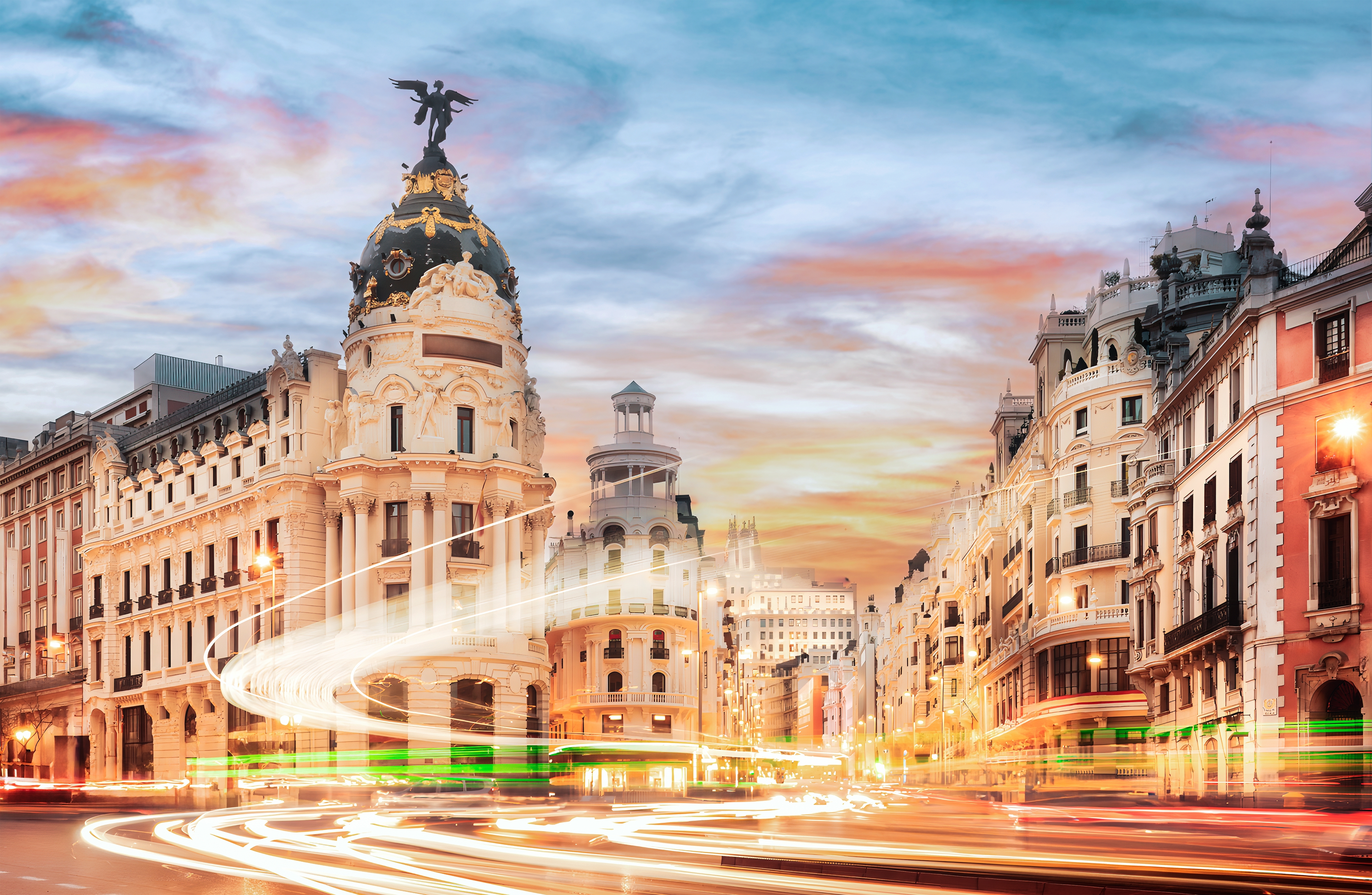 Den berømte Gran Via i Madrid ved solnedgang med historiske bygninger og dynamiske lysspor fra trafikken