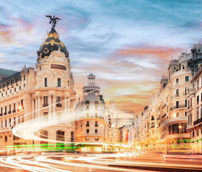 Den berømte Gran Via i Madrid ved solnedgang med historiske bygninger og dynamiske lysspor fra trafikken