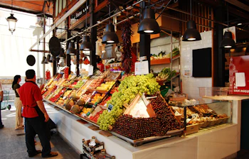 Traditionelt madmarked i Madrid med farverig udstilling af friske frugter og grøntsager ved en markedsbod