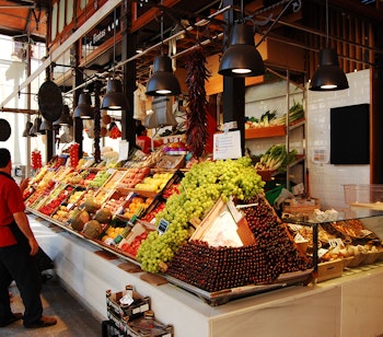 Traditionelt madmarked i Madrid med farverig udstilling af friske frugter og grøntsager ved en markedsbod