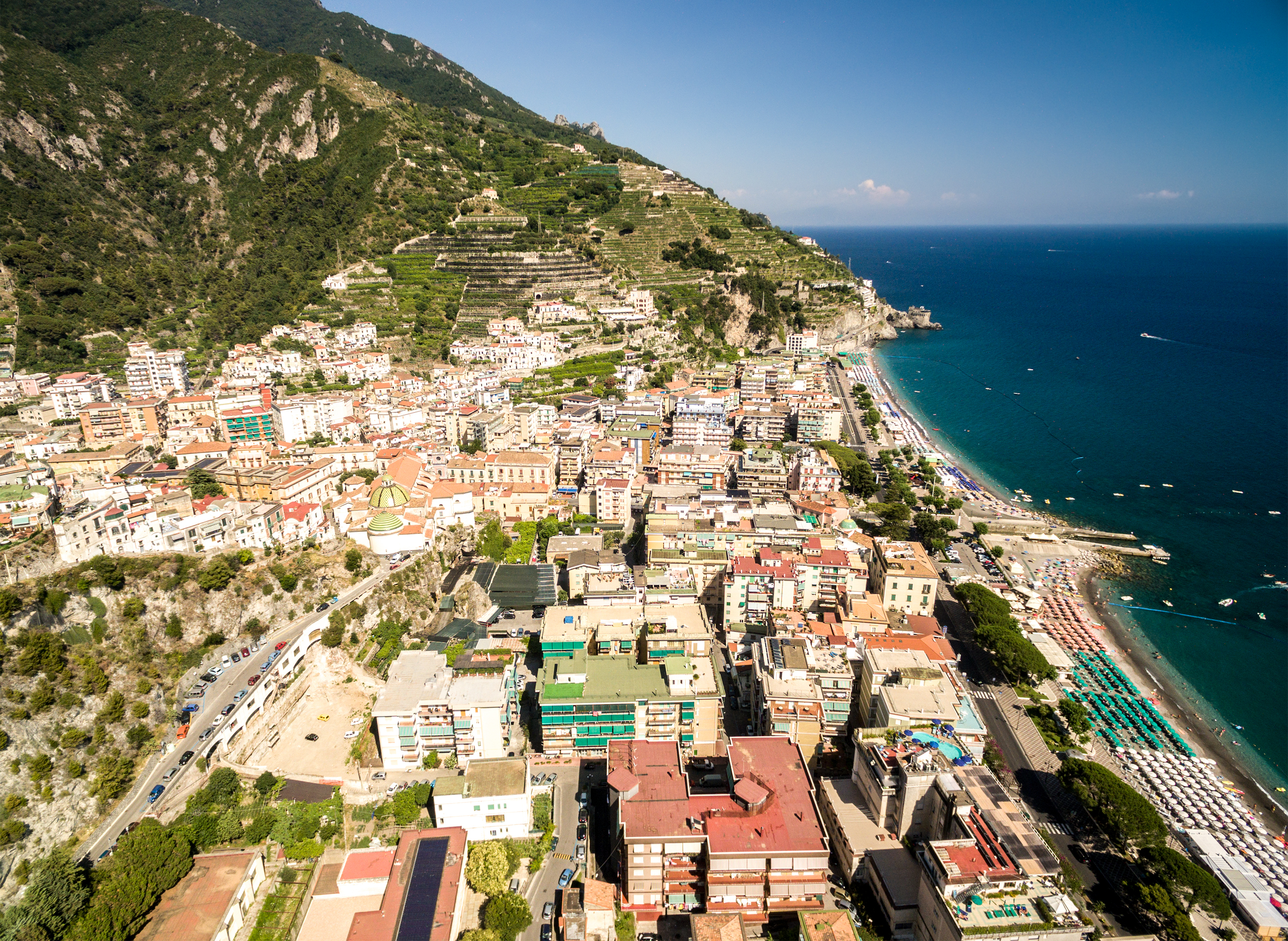 Luftfoto af den charmerende by Maiori på Amalfikysten i Italien med farverige bygninger ned ad grønne bjergsider til det turkisblå Middelhav