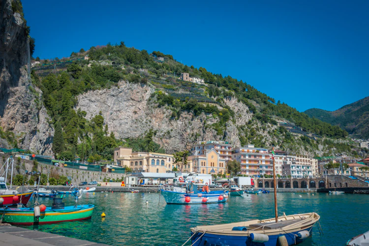 Farverige fiskerbåde i havnen i Maiori på den smukke Amalfikyst i Italien med dramatiske klipper og grønne terrasser i baggrunden