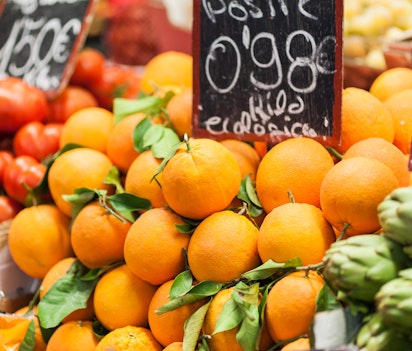 Friske spanske appelsiner med grønne blade udstillet til salg på et traditionelt frugtmarked i Malaga, Andalusien