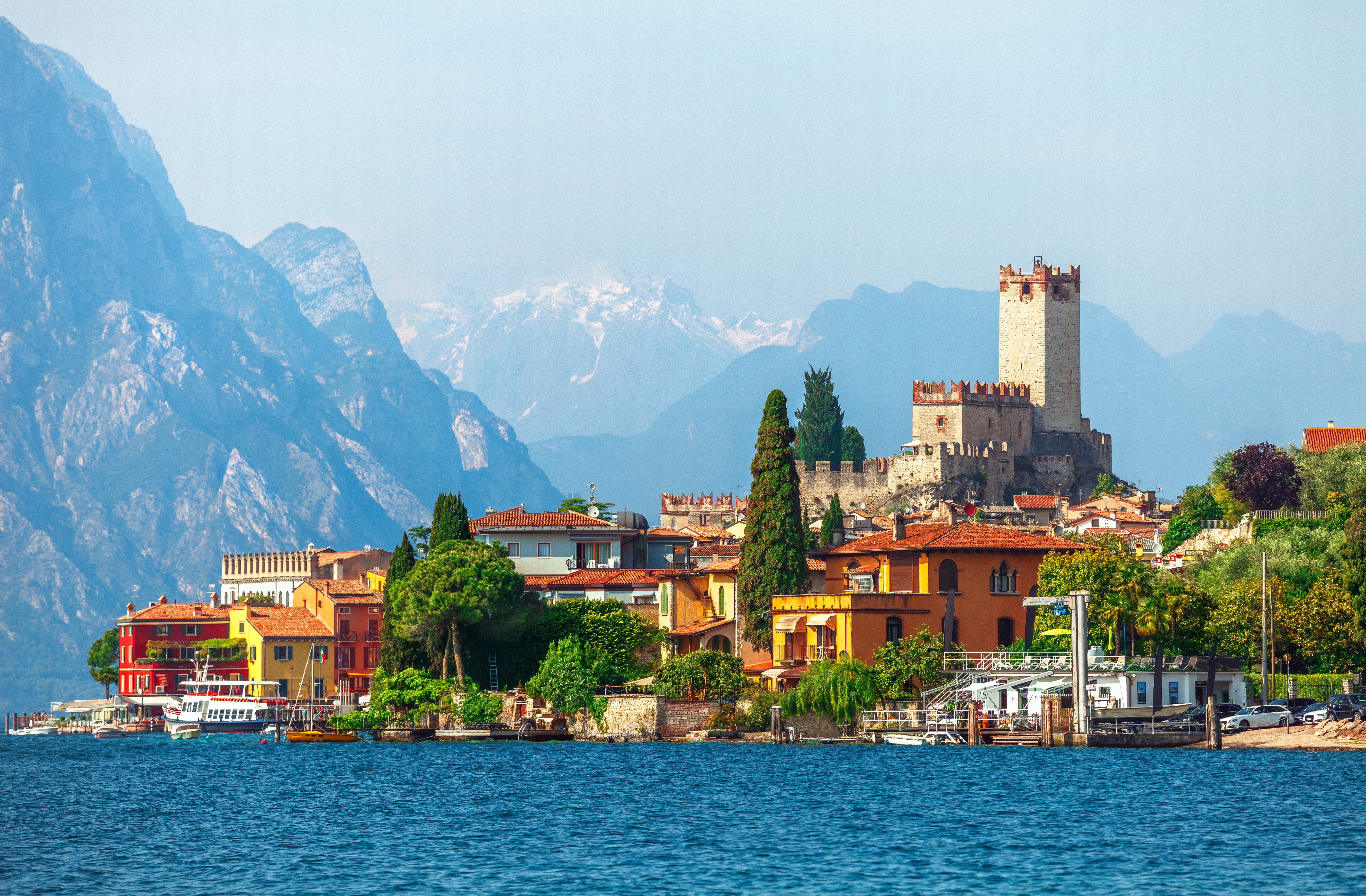 Idyllisk udsigt over Malcesine by med det historiske Scaliger-slot, farverige huse langs Gardasøens bred og sneklædte bjerge i baggrunden, Veneto-regionen, Italien