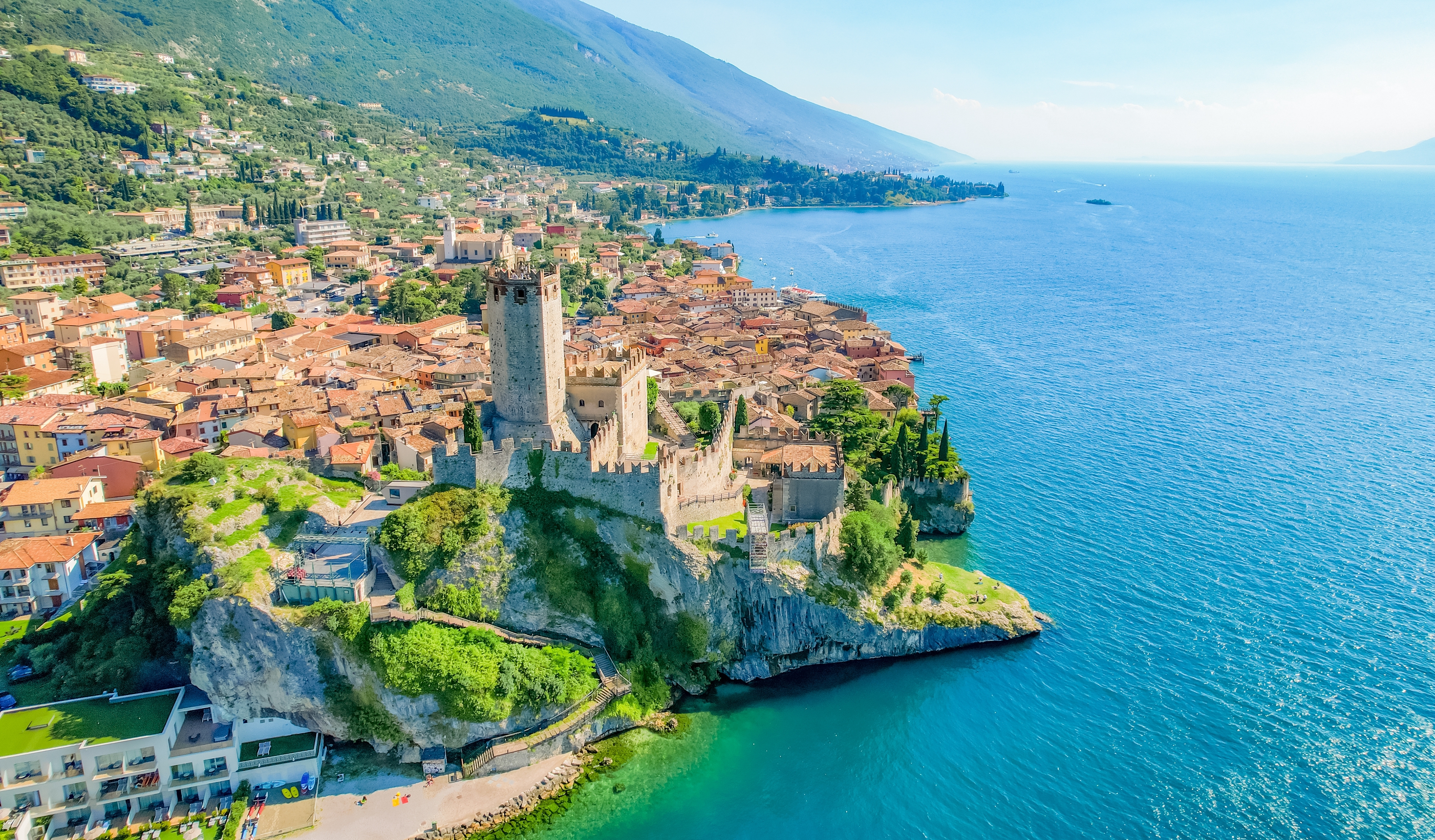 Luftfoto af det historiske Scaliger Slot i Malcesine på en klippeskrænt ud over det blå Gardasø i Italien