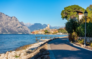 Idyllisk udsigt over Malcesine by med det middelalderlige slot ved Gardasøens bred og bjerge i baggrunden
