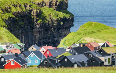 Idyllisk udsigt over den farverige landsby Gjógv med grønne bjerge på Færøerne