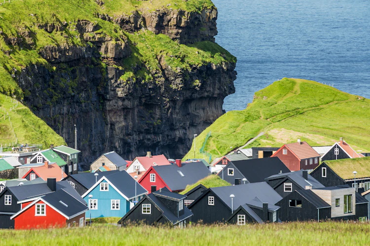 Idyllisk udsigt over den farverige landsby Gjógv med grønne bjerge på Færøerne