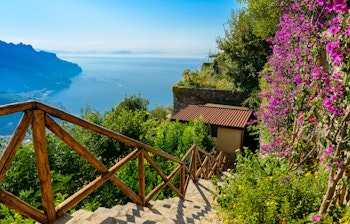 Malerisk stentrappe blandt blomstrende træer med udsigt over Amalfikysten i Ravello, Italien