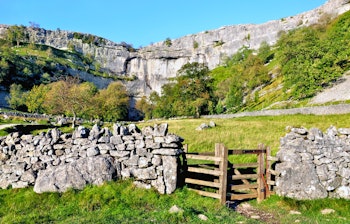 Imponerende kalkstensklipper ved Malham Cove i Yorkshire Dales nationalpark, England med smuk udsigt over det engelske landskab