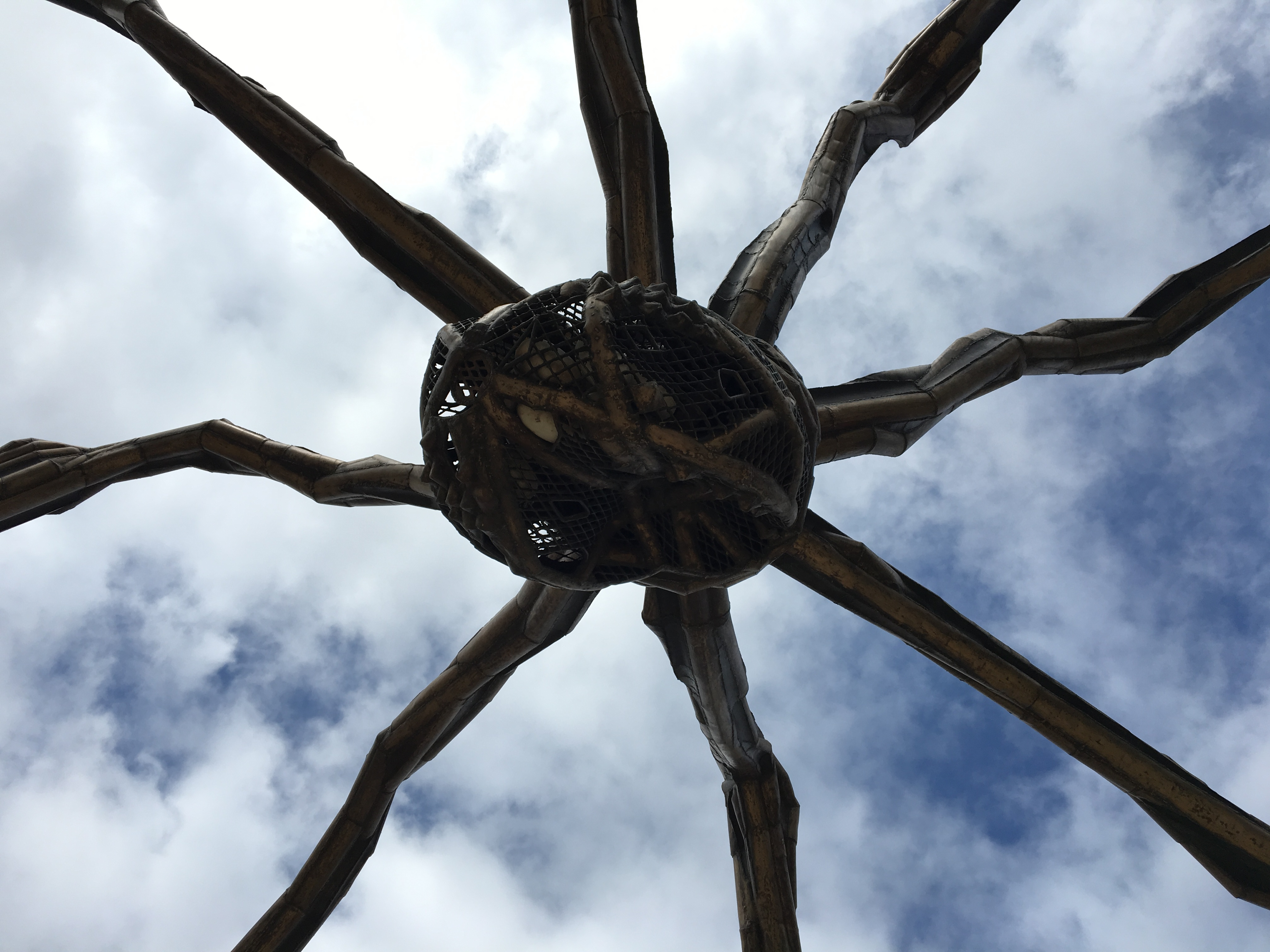 Kig op mod den ikoniske Maman edderkop-skulptur mod en skyet blå himmel i Bilbao, Spanien