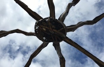 Kig op mod den ikoniske Maman edderkop-skulptur mod en skyet blå himmel i Bilbao, Spanien