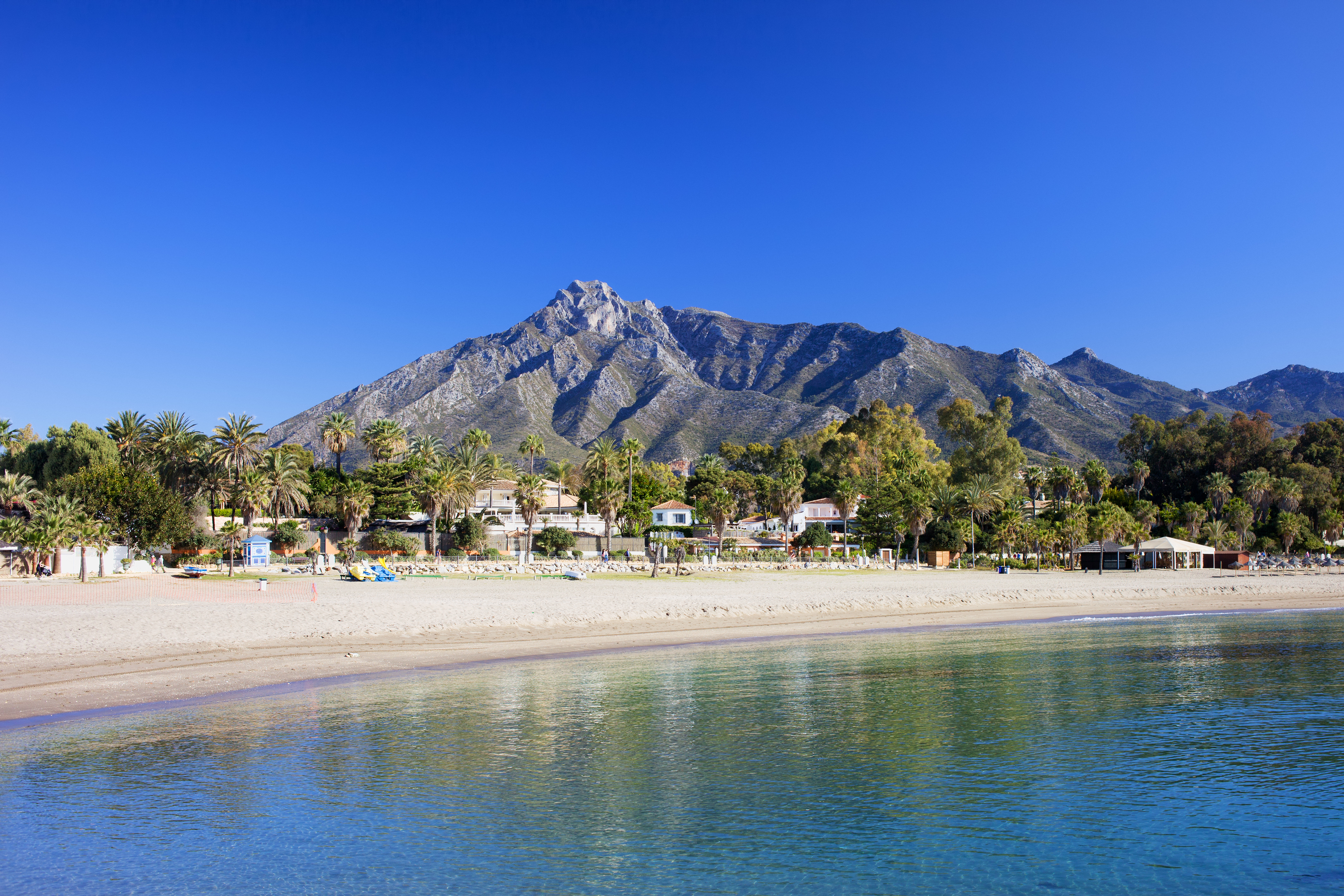 Smuk Marbella strand med krystalklart middelhavsvand og bjerglandskab i Costa del Sol Spanien