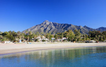 Smuk Marbella strand med krystalklart middelhavsvand og bjerglandskab i Costa del Sol Spanien