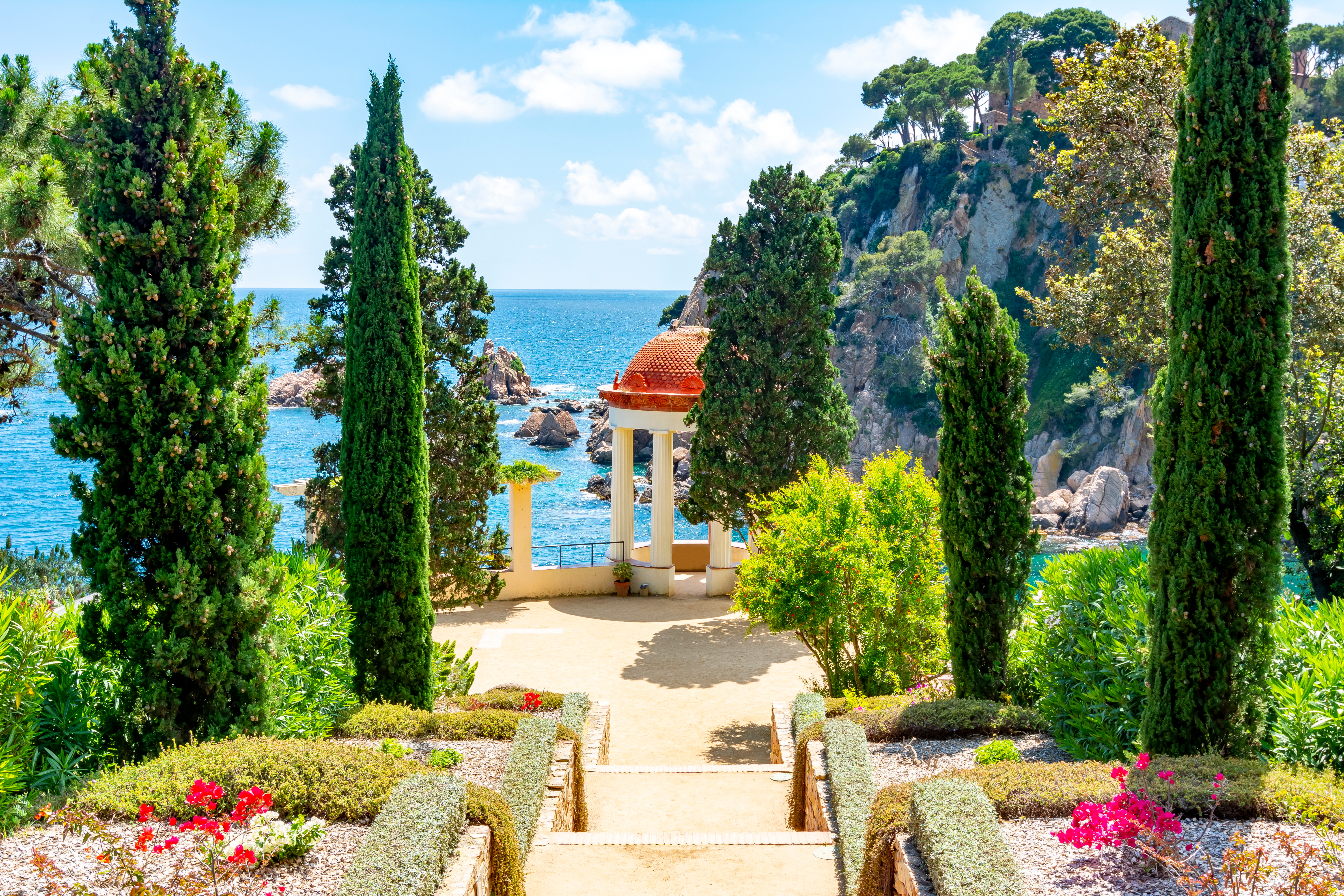 Marimurtra botanisk have i Blanes nær Barcelona med elegant hvid pavillon med udsigt over Middelhavet, omgivet af høje cyprestræer og farverige blomster på Costa Brava, Spanien