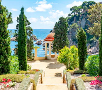 Marimurtra botanisk have i Blanes nær Barcelona med elegant hvid pavillon med udsigt over Middelhavet, omgivet af høje cyprestræer og farverige blomster på Costa Brava, Spanien