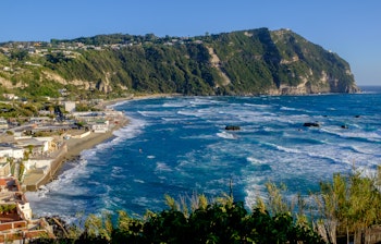 Panoramaudsigt over den gyldne Maronti-strand med turkisblåt vand og klippekyster på øen Ischia i Italien