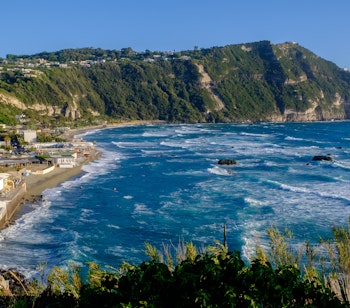 Panoramaudsigt over den gyldne Maronti-strand med turkisblåt vand og klippekyster på øen Ischia i Italien