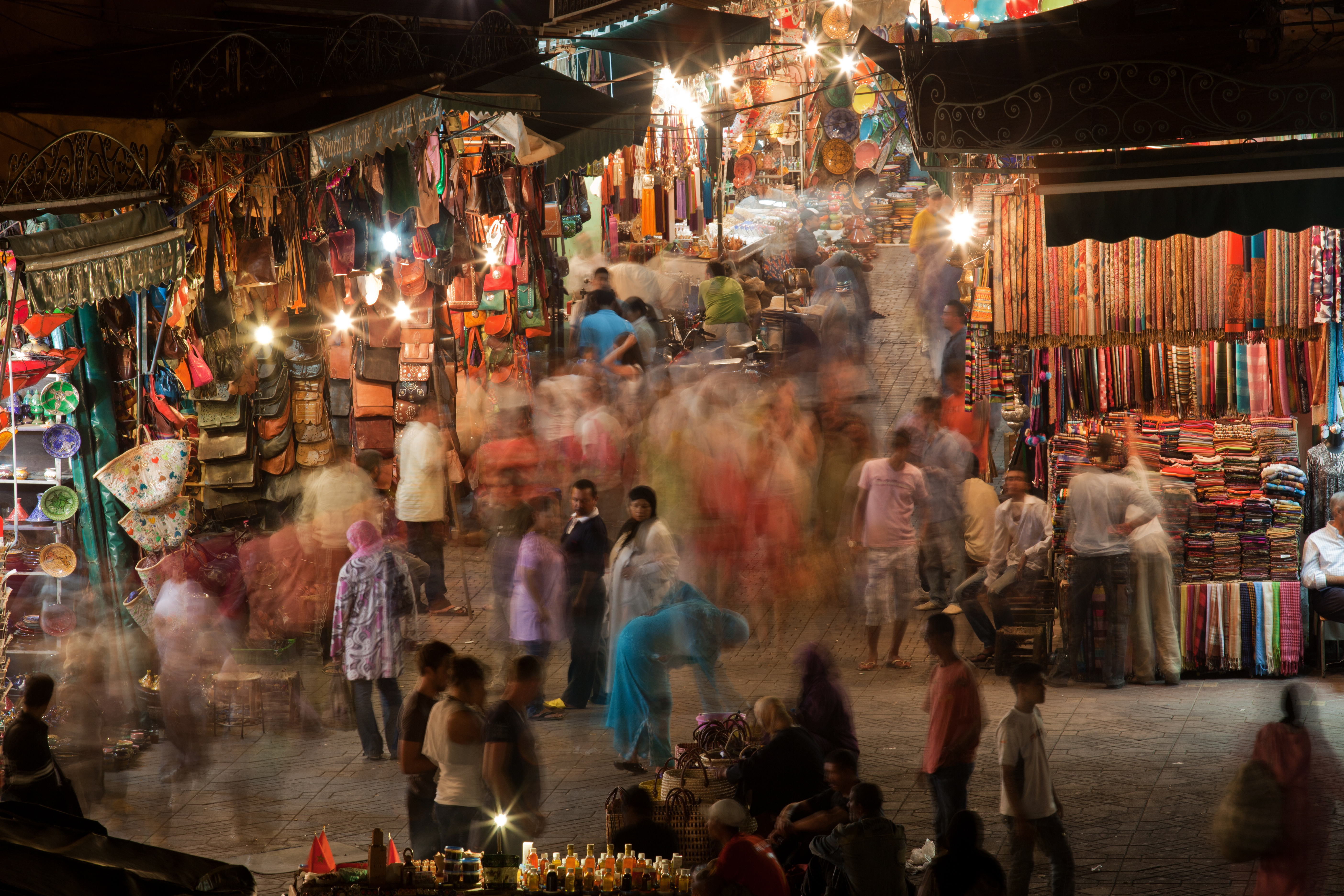 Travlt aftensmarked på Djemaa el-Fna pladsen i Marrakech med farverige tekstiler og traditionelle marokkanske souks